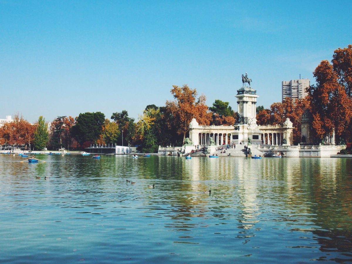 A vast blue lake surrounded by historic buildings and fall foliage.