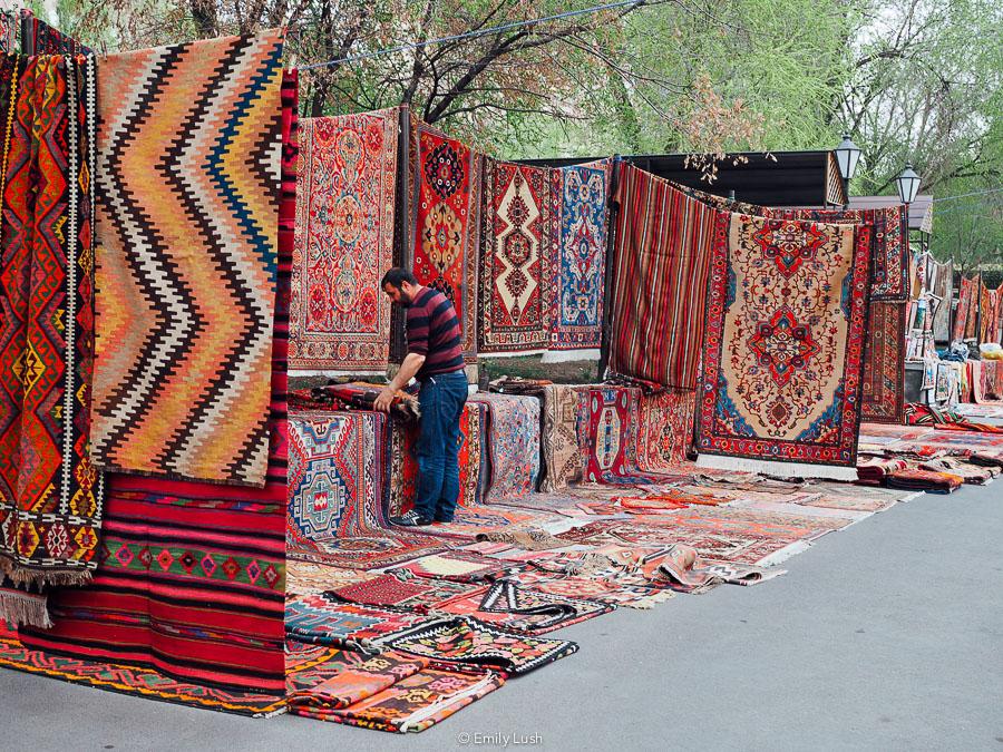 A vendor sells carpets at the Yerevan Vernissage market.