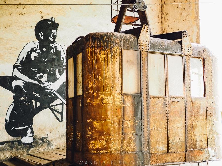 A rust-coloured cablecar and a street art mural in Chiatura, Georgia.