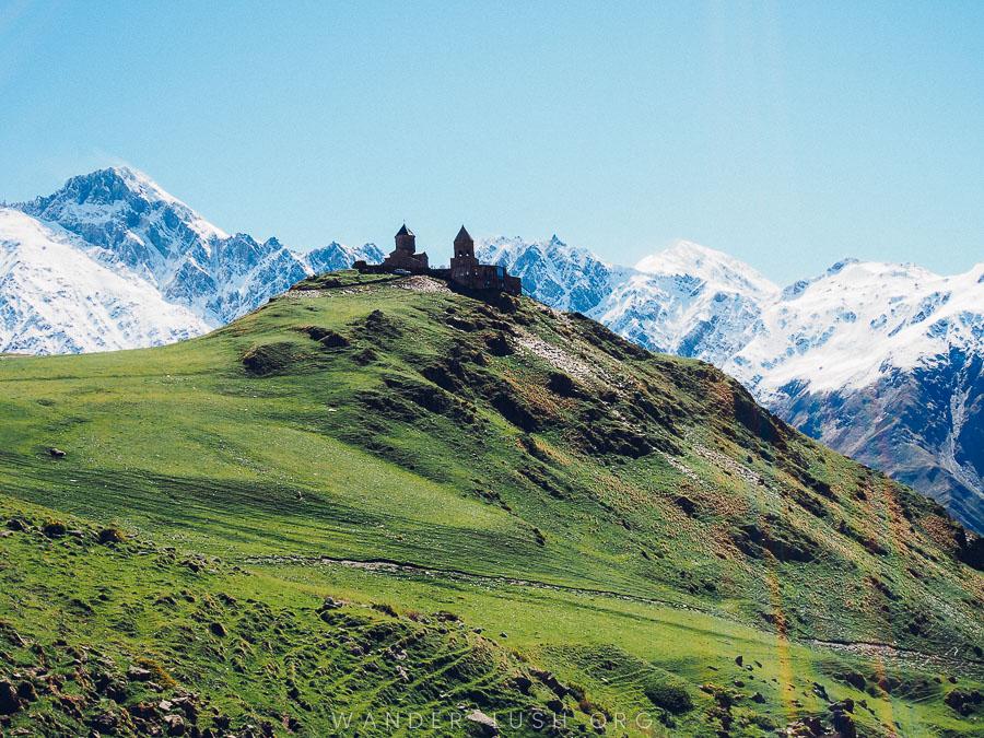 A church sits on top of a green mountain in Kazbegi, a day trip from Tbilisi.