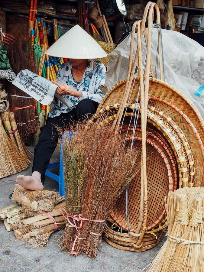 A woman reads a newspaper inside her stall in Hanoi Old Quarter.