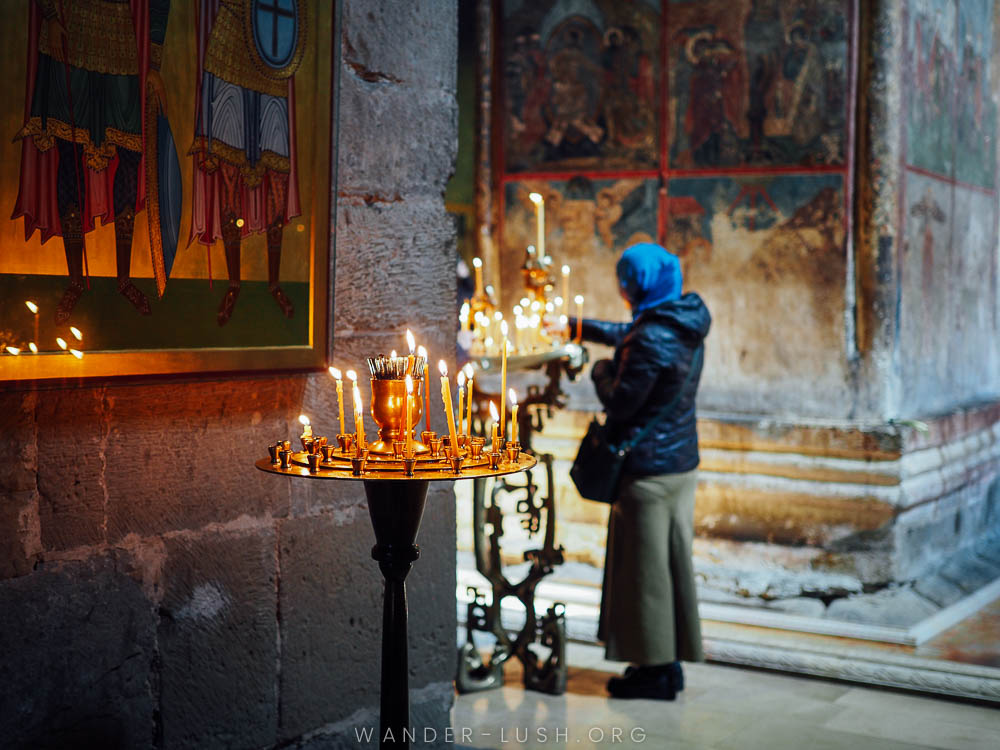 A woman lights candles inside a church.