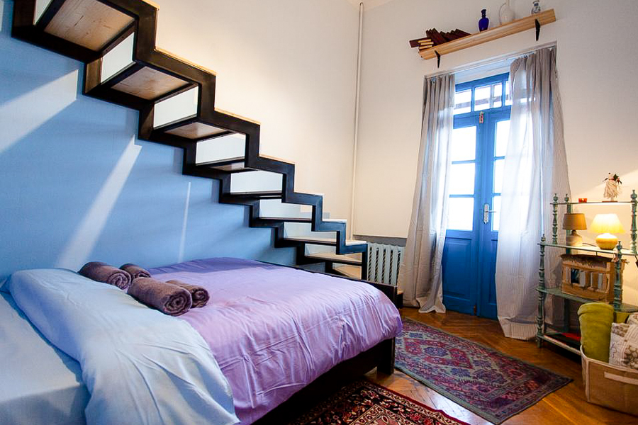 A homely bedroom with a bed, floor rugs, and a blue door.