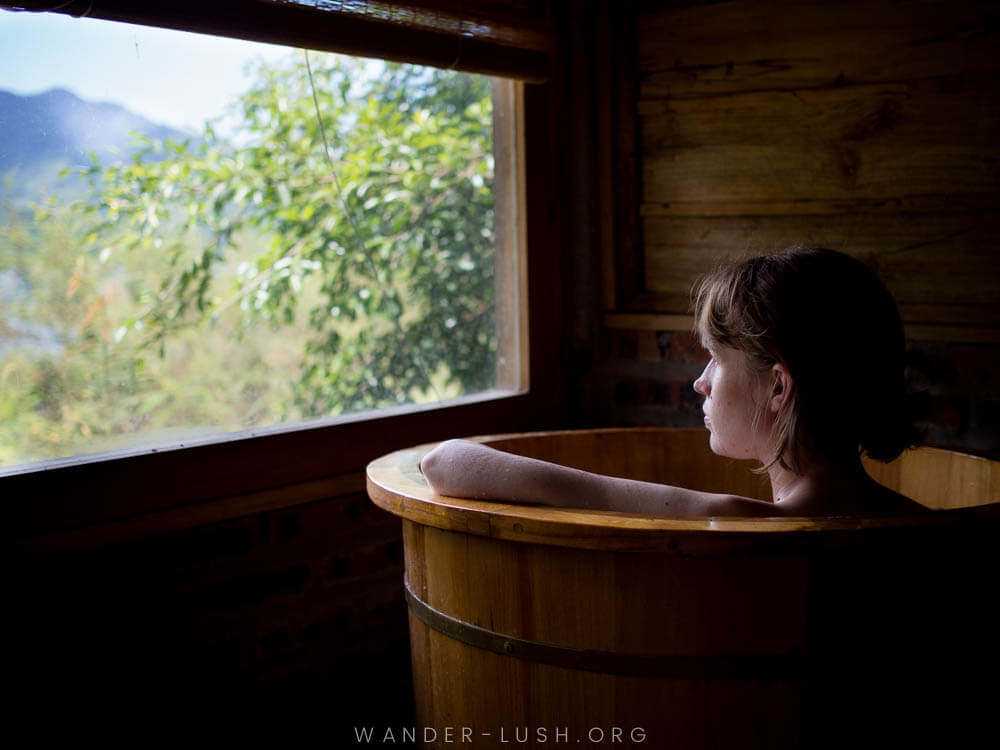 A woman sits in a traditional wooden bath tub at a homestay in Northern Vietnam.