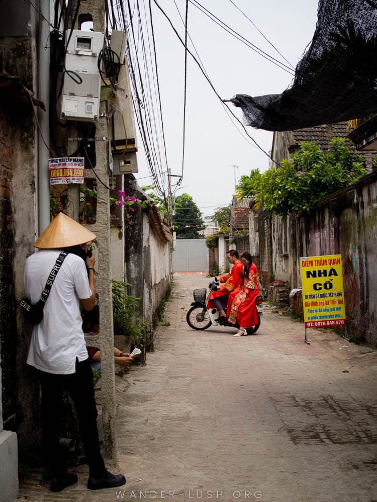 Two people pose for a photo on the back of a scooter in Duong Lam Ancient Village near Hanoi.