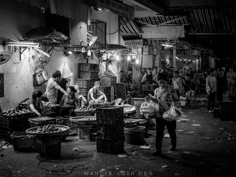 Vendors gather around baskets of fresh produce at the Long Bien Night Market in Hanoi, Vietnam.