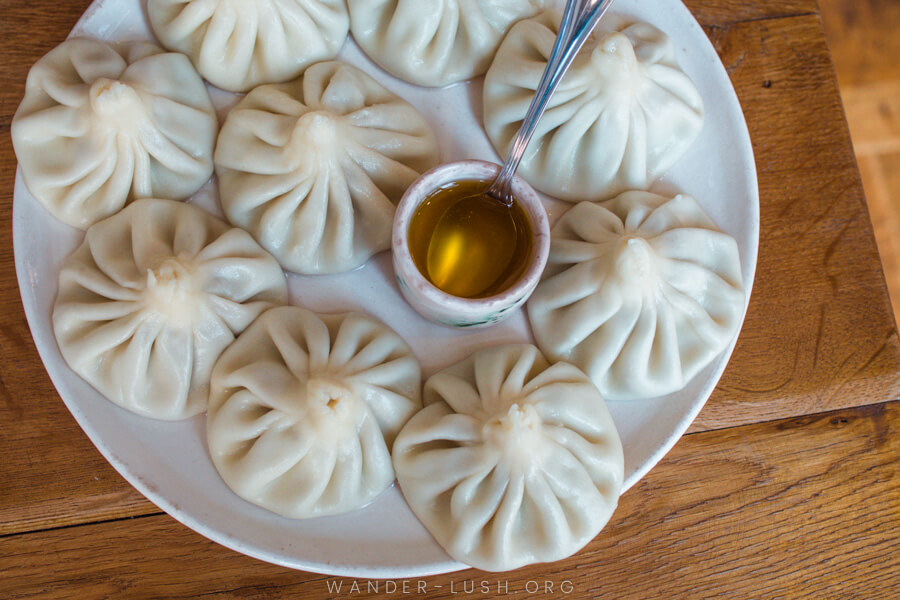 A plate of khinkali meat dumplings on a wooden restaurant table in Tbilisi, Georgia.