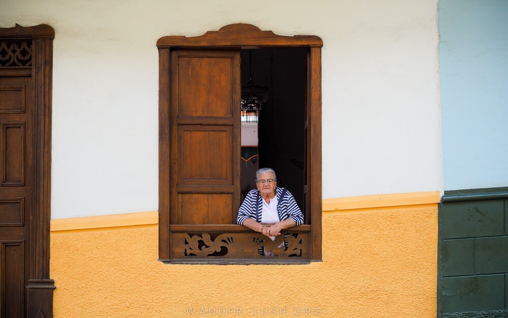 A woman peers out a wooden window in Jerico, Colombia.