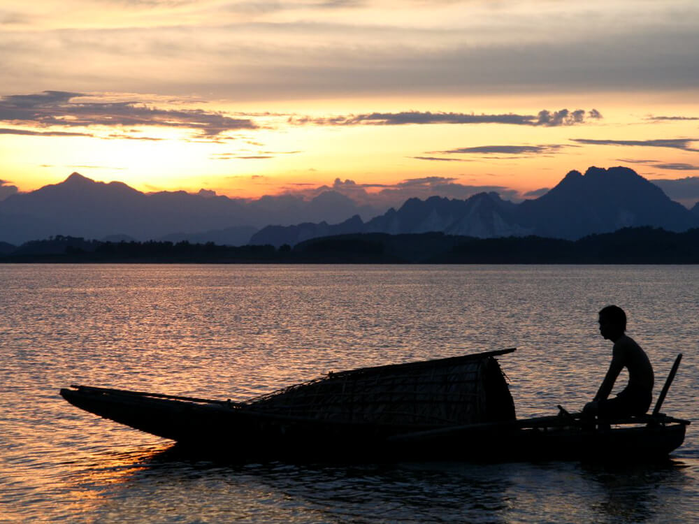 A man in a sampan travels along the water on Thac Ba Lake.