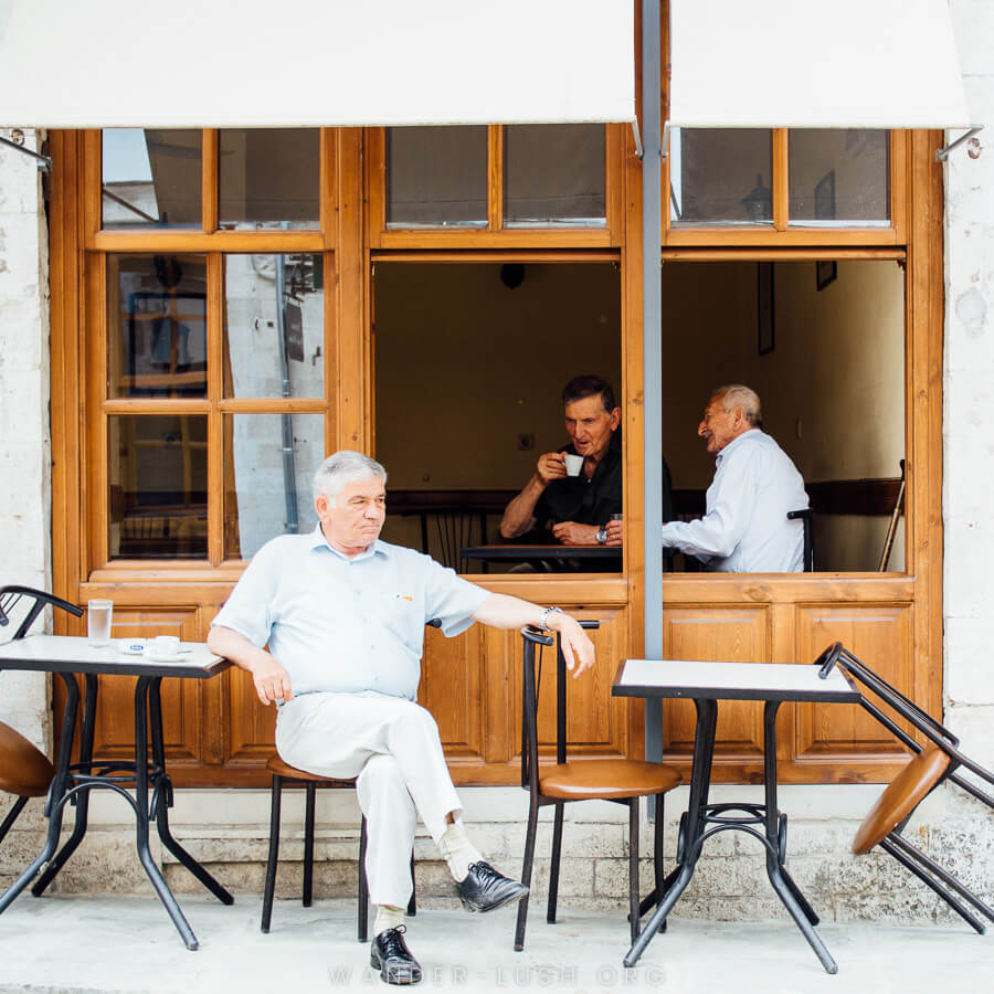 Three men sit in a cafe sipping coffee.