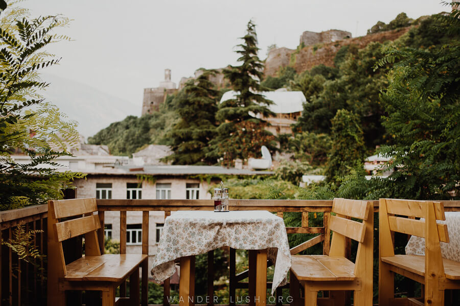 Tables and chairs set on a terrace with picturesque views of Gjirokaster castle and town.