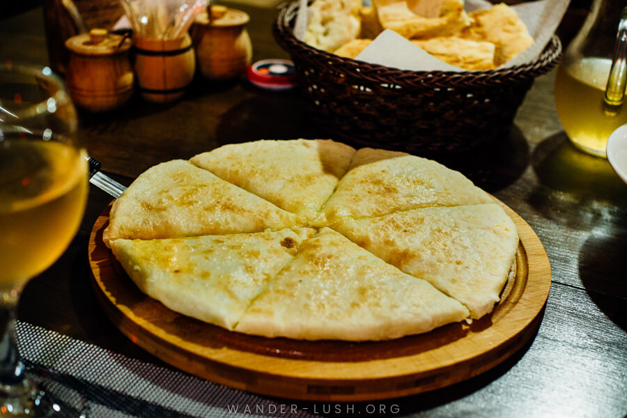 A round Imeretian Khachapuri presented on a wooden board.