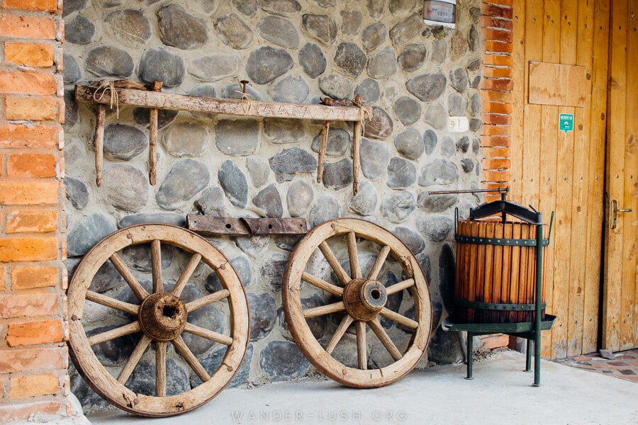 Old wooden wheels propped up against a brick building at Baia's Wine.