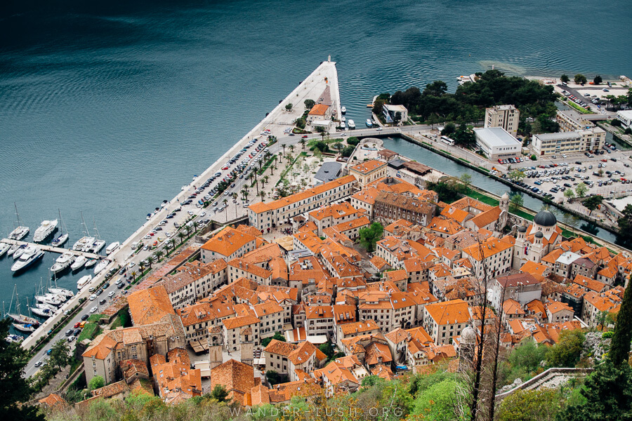A triangle-shaped bay and an old town made up of hundreds of orange roofs viewed from above.
