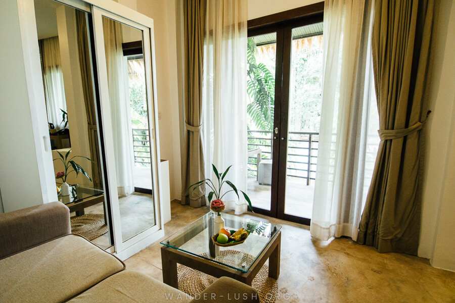 A hotel room with a wardrobe, sofa and curtains.