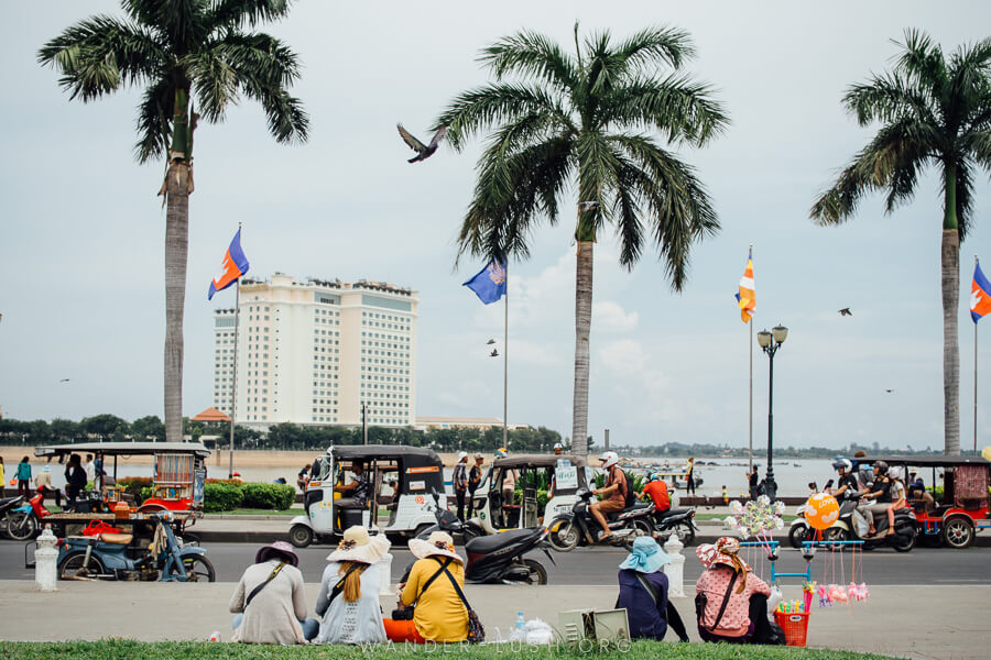 Three tall palm trees and a group of women sitting underneath.