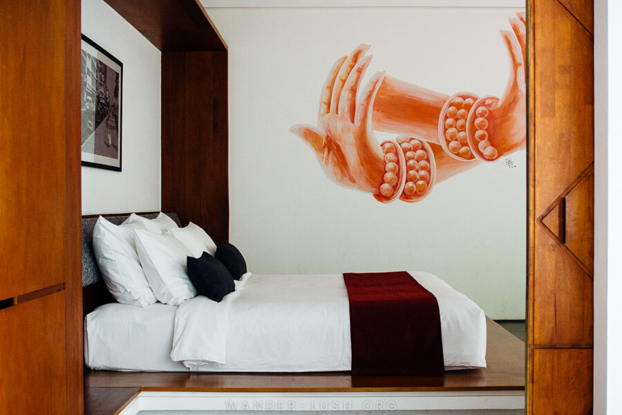 A large bed with timber doors and a pink artwork on the wall.