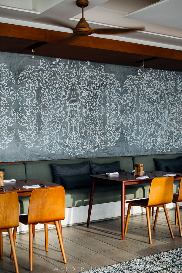 The interior of a restaurant, with dark walls and timber chairs.
