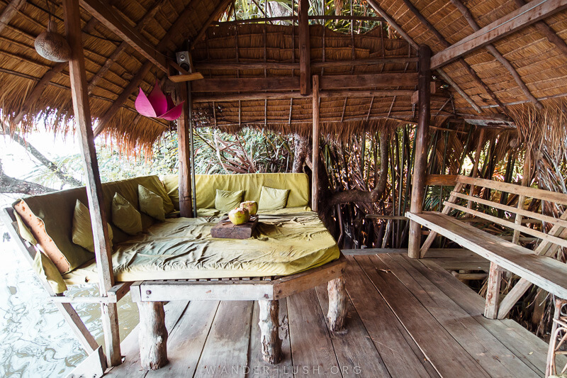 A green day bed inside a rustic bamboo shack.