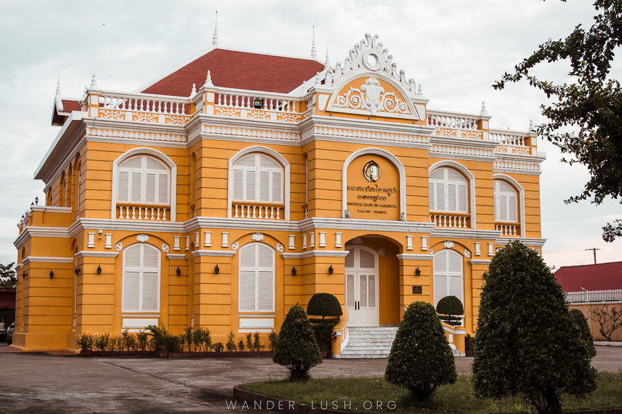 A beautiful yellow building with white detailing and manicured gardens.