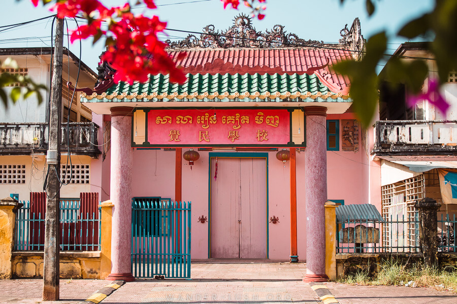 A pink building with a colourful roof and Chinese script above the door.