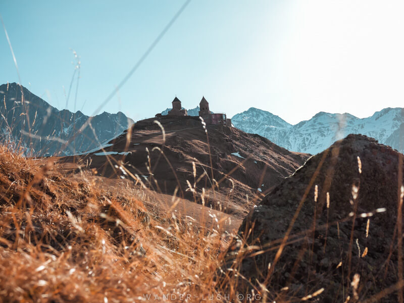 The silhouette of a church against a brown mountain backdrop.