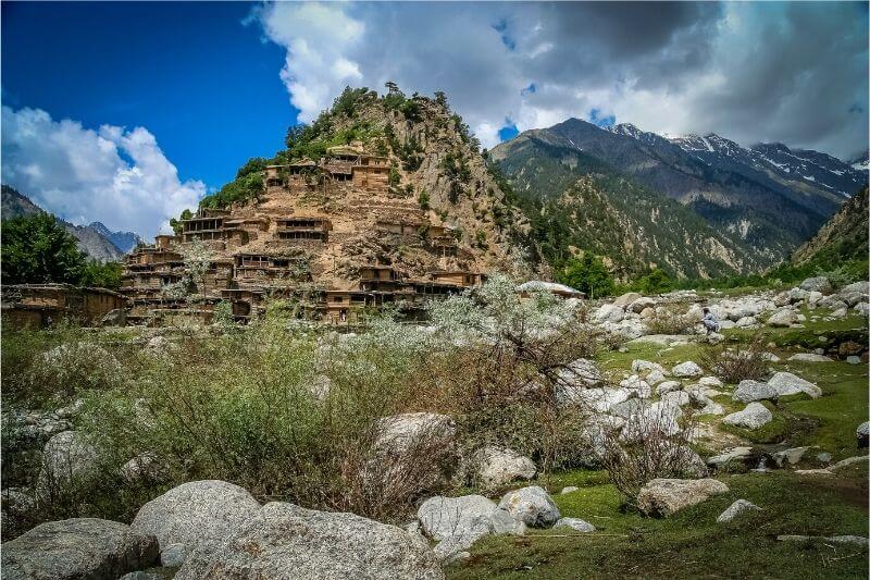 Wooden houses cling to the side of a hill in Pakistan.