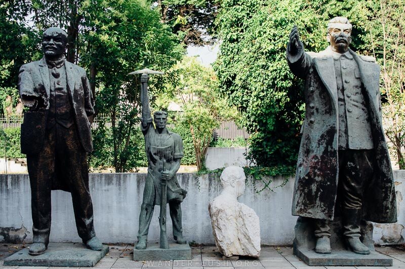 Four damaged statues in a garden.