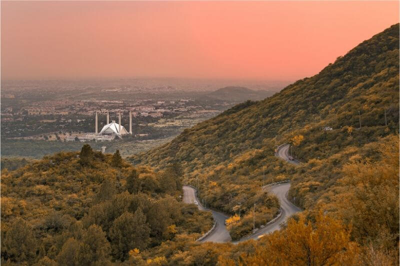 A red sky at dusk with a mosque visible in the valley.