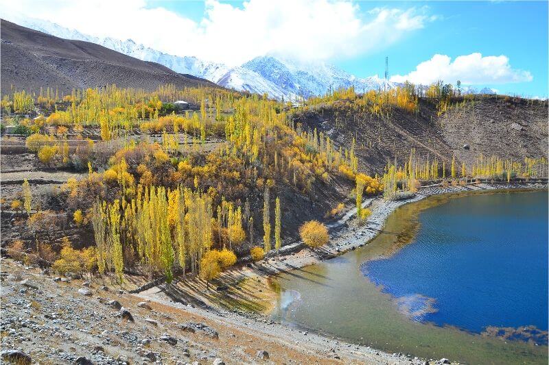 A beautiful blue lake surrounded by fall foliage, one of the most beautiful places in Pakistan.