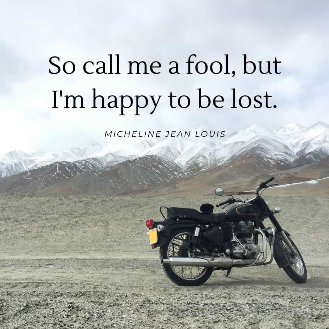 A motorbike sits in front of snow capped mountains.