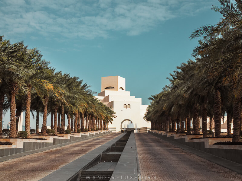 The Museum of Islamic Art in Doha, Qatar, a modern white building with rows of palm trees in front.