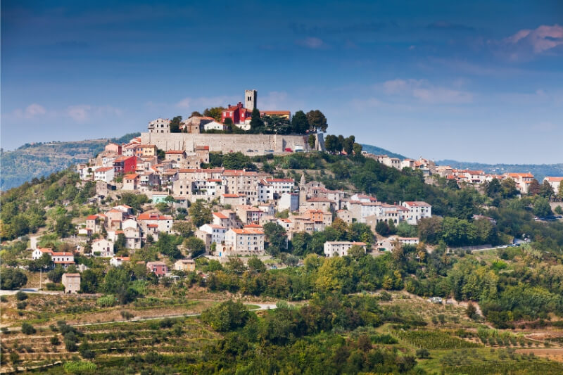 A beautiful white city and fortified castle atop a green hill in Istria, Croatia.