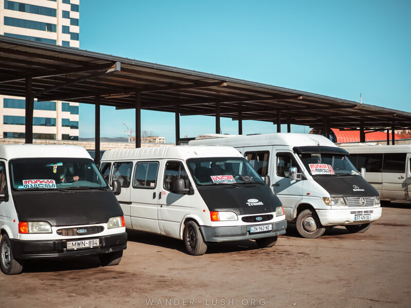 Three white vans in a row at Didube Bus Station in Tbilisi.