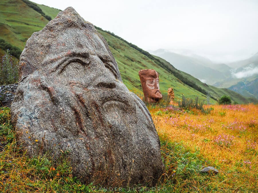 Large stone sculptures depicting different faces scattered around a field near Juta in Georgia.