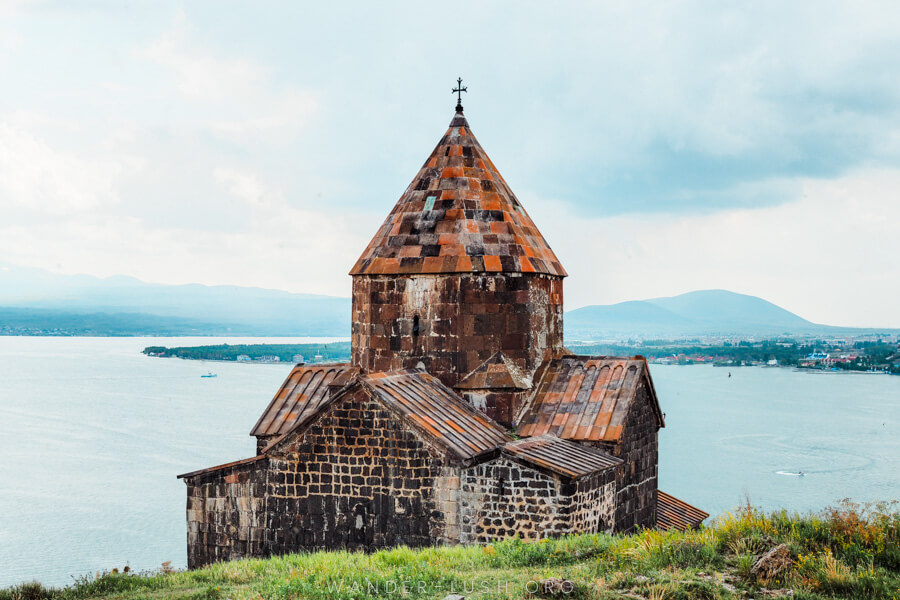 A stone church on the edge of a blue lake in Sevan, Armenia.