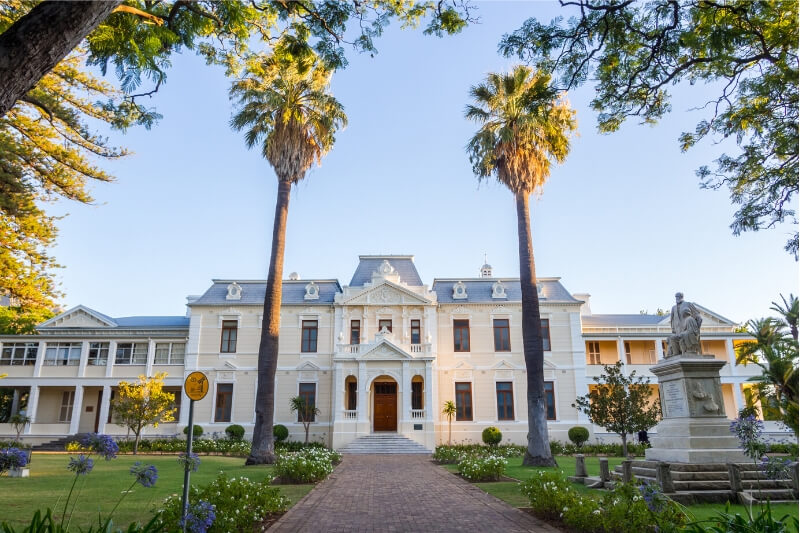 A beautiful heritage building in Cape Town surrounded by tall palm trees.