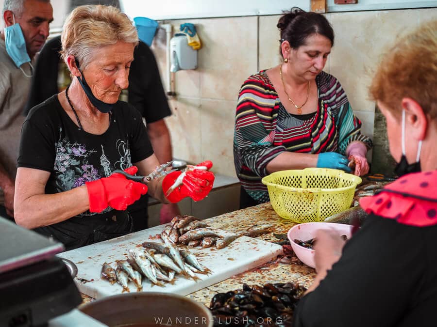 Three women cleaning fish inside the Batumi Fish Market.