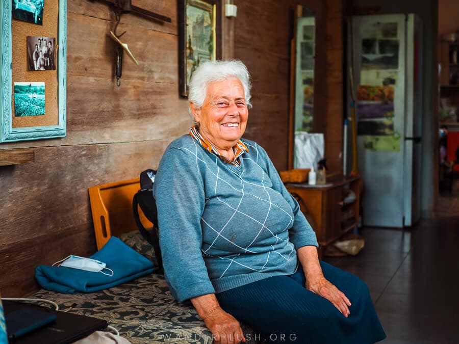 A smiling woman sits on a daybed in Guria, Georgia.