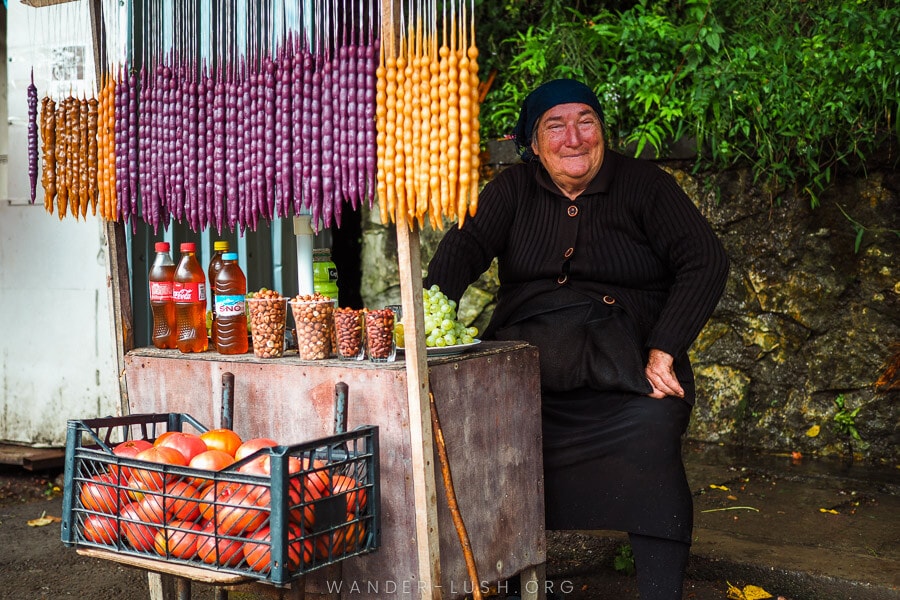 A woman sells fruit and snacks at a roadside stall in Georgia.