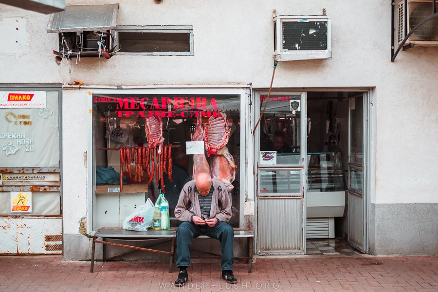 A man sits in front of a butcher's shop in Bitola, North Macedonia.