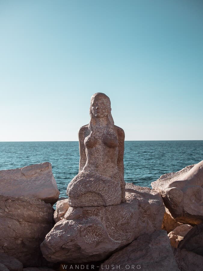 A stone sculpture of a mermaid on the dock in Piran.
