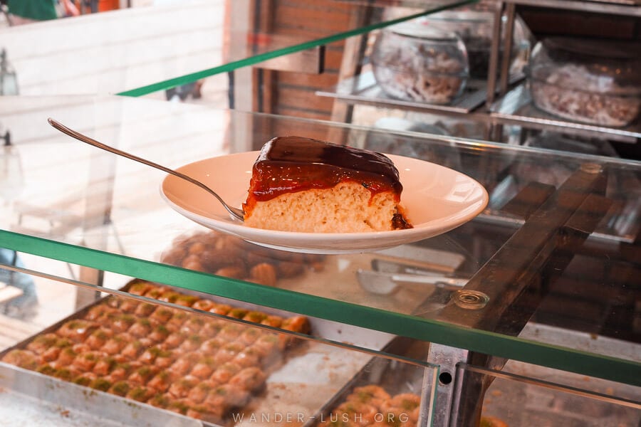 A slice of trilece cake on a glass counter in a sweet shop in Skopje.
