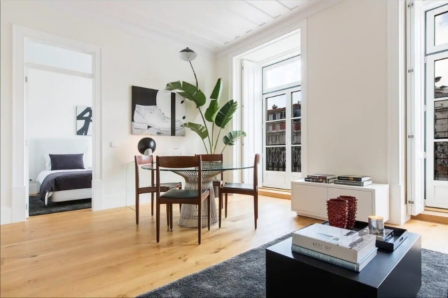 A modern apartment interior with tall windows and wooden floors.
