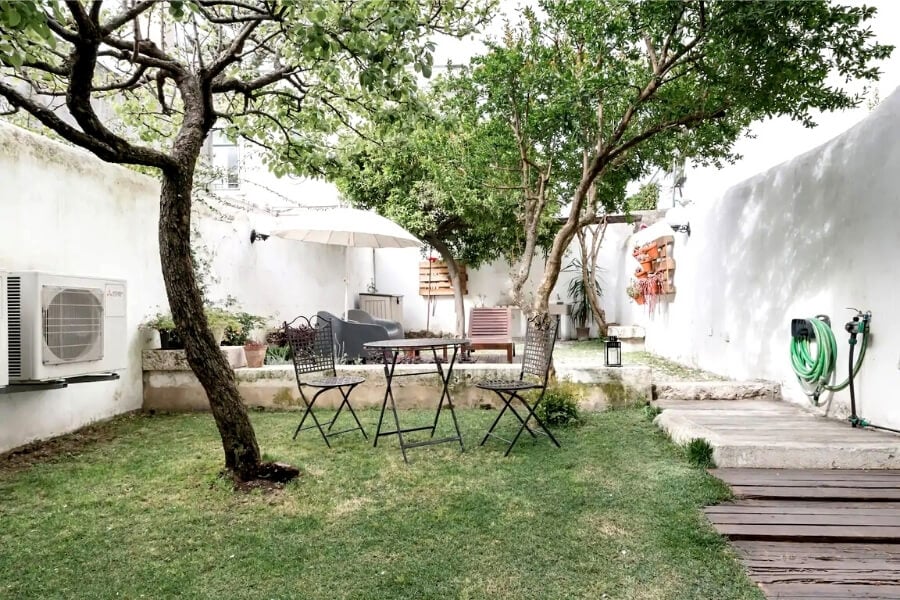 A private courtyard in Lisbon with a beautiful tree and garden furniture.