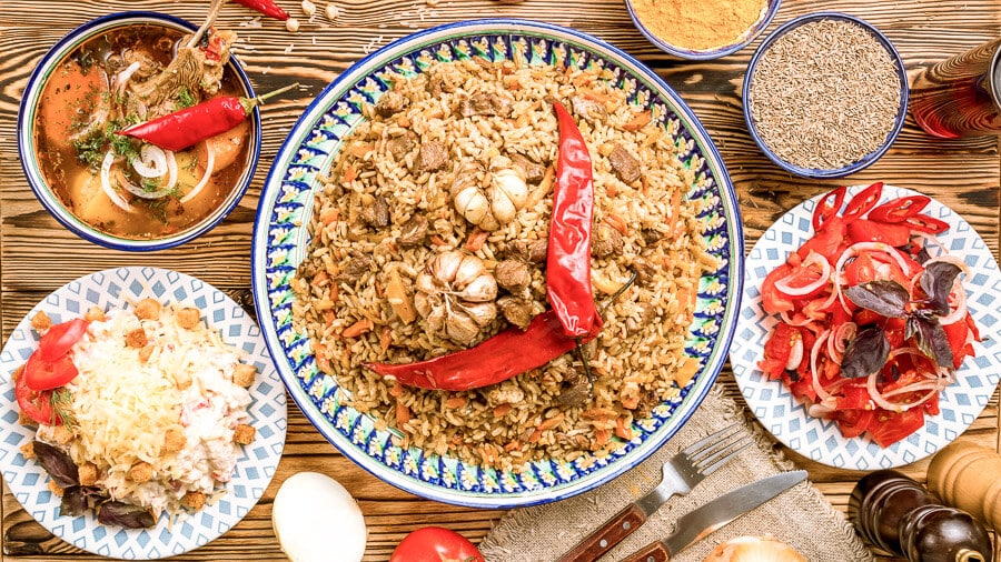A table laid with plov and various Uzbekistani traditional food ingredients.