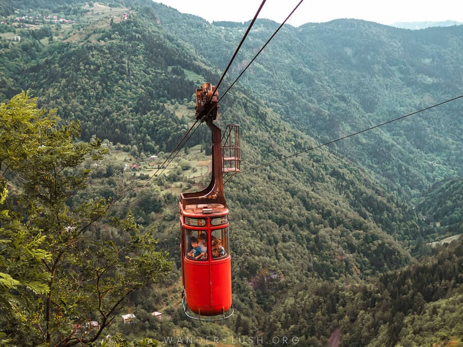 A red cable cars whisks people over a verdant valley in Georgia's Upper Adjara.