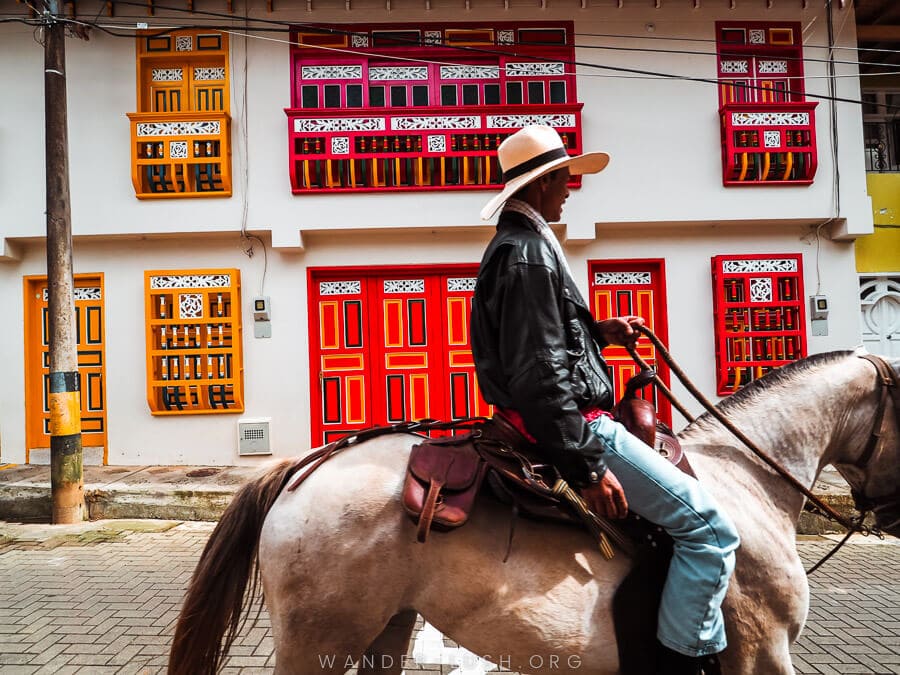 A man rides his horse in front of colourful houses in Jerico, Colombia.