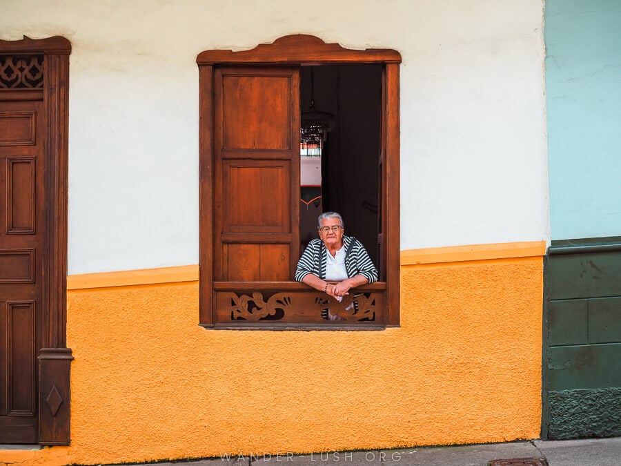 A woman looks out the window of her colourful house in Jerico, Colombia.