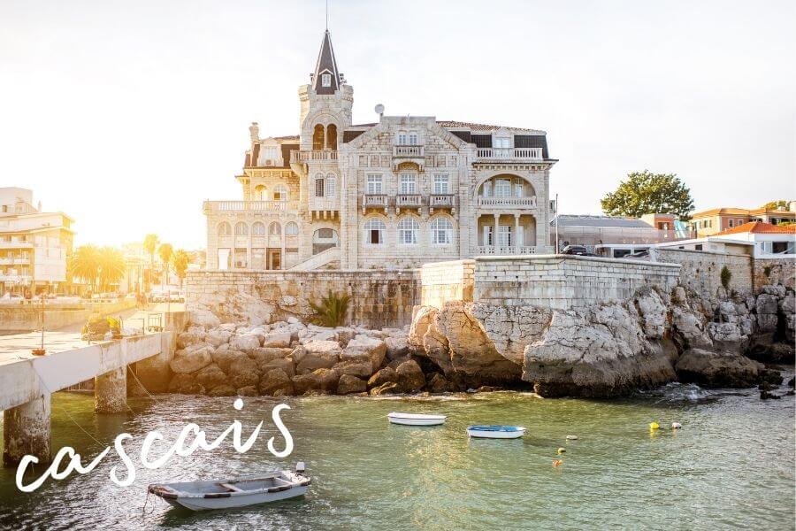Boats float on the water in front of a grand building in Cascais, Portugal.